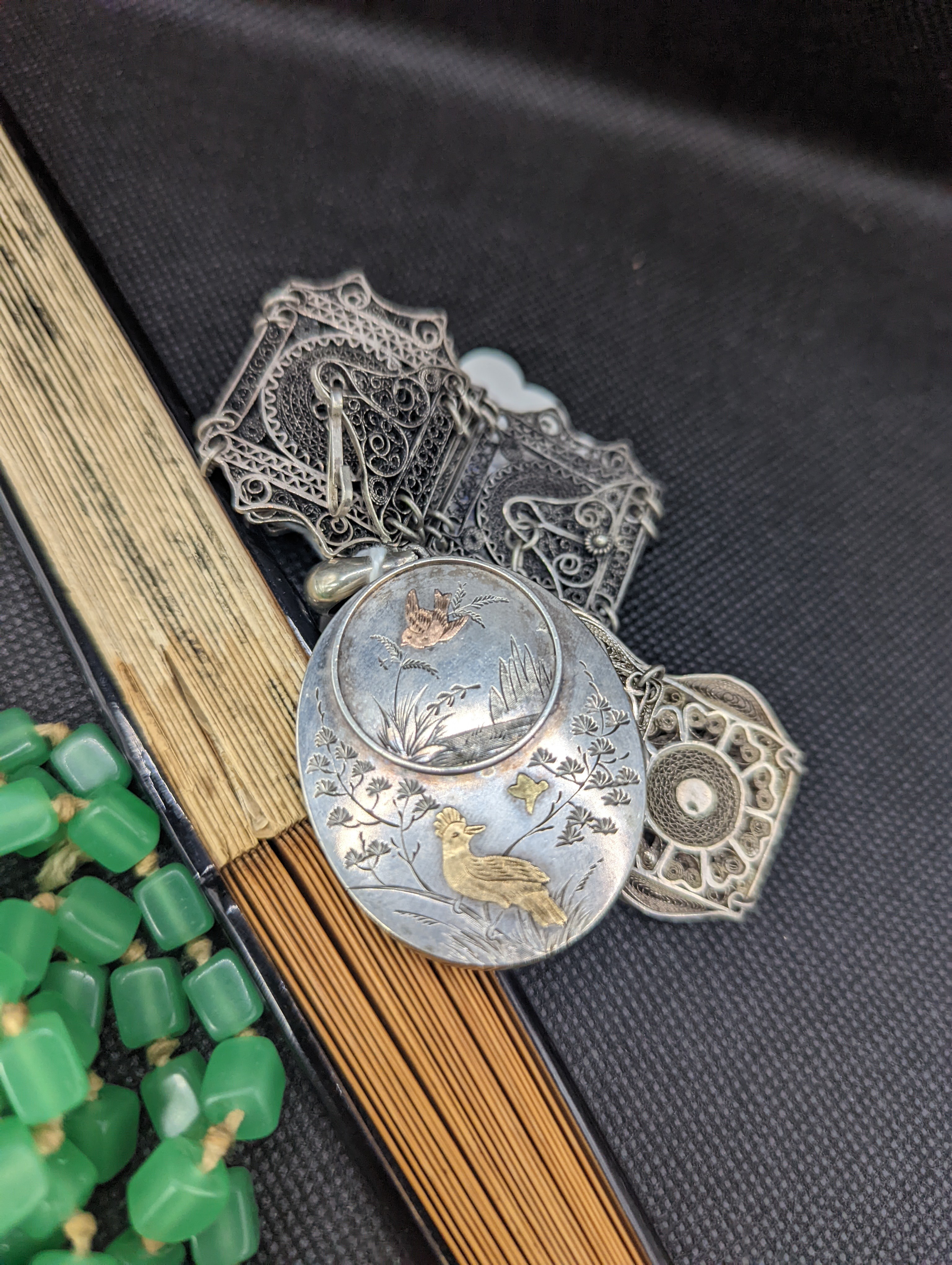 A white and yellow metal oval locket with aesthetic decoration, 44mm and a small quantity of assorted costume jewellery including and a fan.